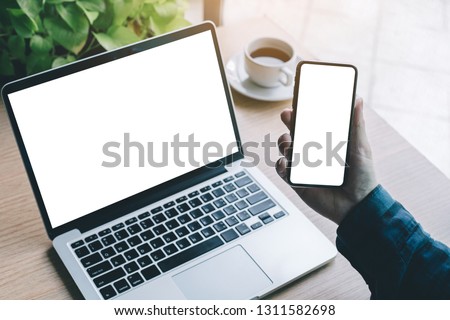 mockup image computer,cell phone and typing with blank screen for text,using laptop contact business searching information in workplace on desk in office.design creative work space on wooden desktop