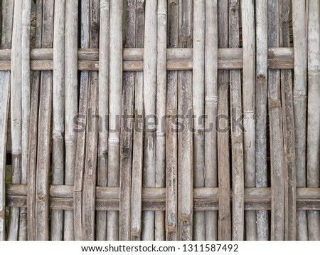 Weathered texture of traditional rural Thai style woven bamboo wall with lattice pattern.