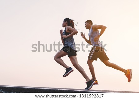 young couple runner running on running road in city park Royalty-Free Stock Photo #1311592817