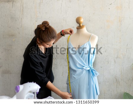 Young designer using measuring tape with clothes dummy, work lifestyle