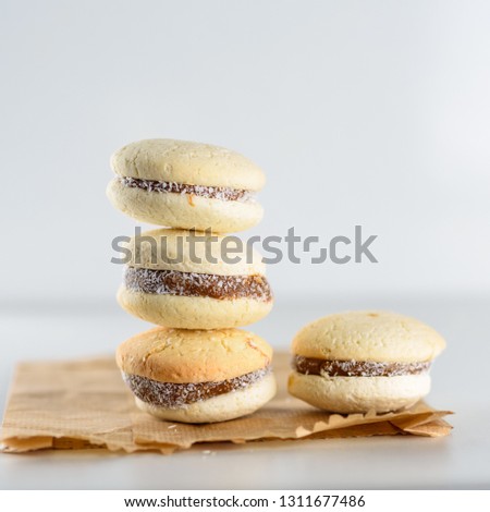 Delicious Argentinian cookies alfajores with cream dulce de leche on the table on paper bag, plastic free. Close up white vanilla macaroons on wooden background. French delicate dessert for breakfast.