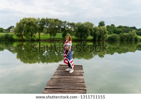 Flag of the USA is a woman. At the lake in the summer.