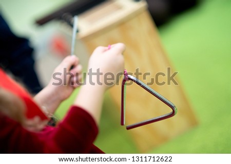 Children's hand holds a triangle percussion musical instrument