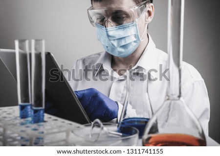 Professional scientist holding a test tube and tablet while making a research