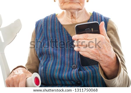 Close up picture of an elderly disabled woman holding a crutch and a smart phone