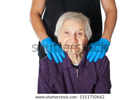 Portrait of a cheerful senior woman having dementia disease, assisted by a male caregiver. Man's hands on patient's shoulder