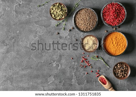Bowls with different aromatic spices on grey background