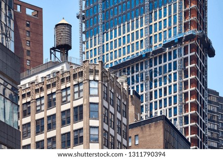 Water tank on an old building roof surrounded by modern skyscrapers in downtown New York, USA.