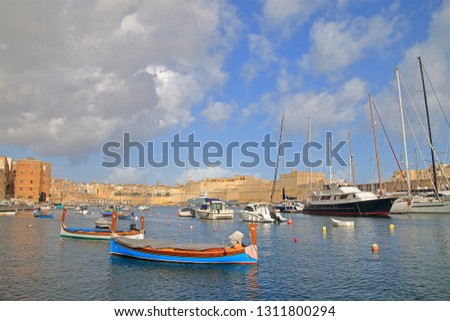 The photo was taken in the month of January on the island of Malta. The picture shows the traditional Maltese boats anchored in the harbor of the island against the background of the architecture.