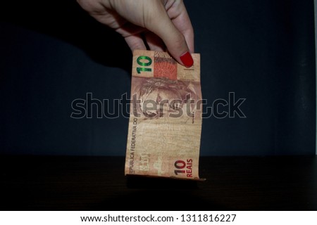 hand holding currency Brazilian Brazil Real money notes, a 10 ten reais note, isolated on black background