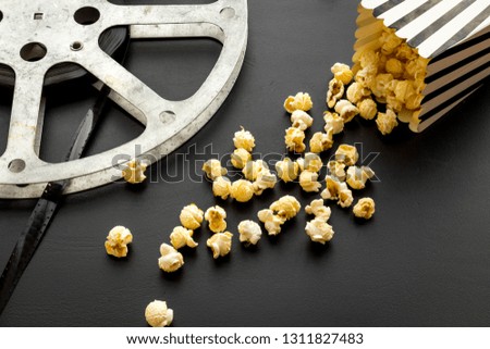 Cinema concept. film stock and popcorn on black background copy space