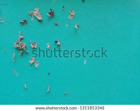 Dry leaves in various shapes on a blue wall with traces of paint brushes