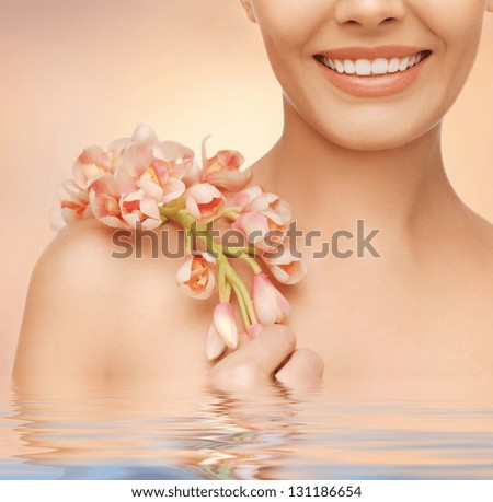 closeup picture of woman's shoulder and hands holding orchid flower