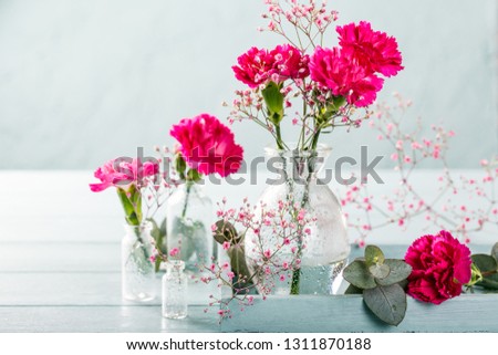 Bouquet of pink carnation in glass vase on light turquoise wooden background. Mothers day, birthday greeting card. Copy space.