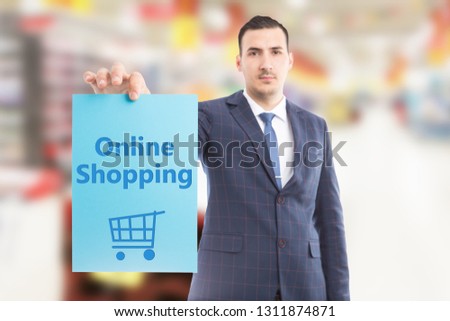 Salesman wearing suit and tie holding online shopping blue paper in hand with cart drawing as digital commerce concept