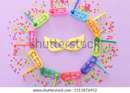Purim celebration concept (jewish carnival holiday) with mask mask over wooden purple background.