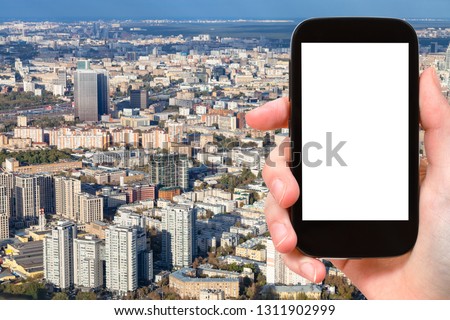 travel concept - tourist photographs of aerial view of northeast of Moscow city from observation deck in autumn on smartphone with empty cutout screen with blank place for advertising