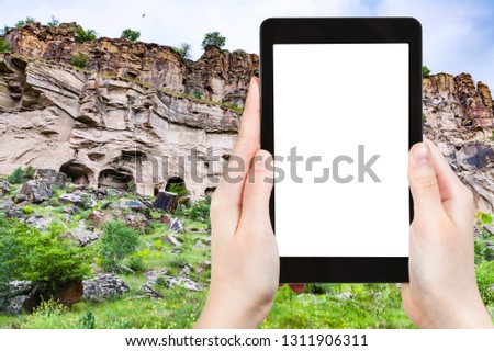 travel concept - tourist photographs of rocks caves in Ihlara Valley of Aksaray Province in Cappadocia in spring in Turkey on smartphone with empty cutout screen with blank place for advertising