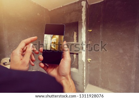 Mobile device with man hands taking picture in tiled bathroom