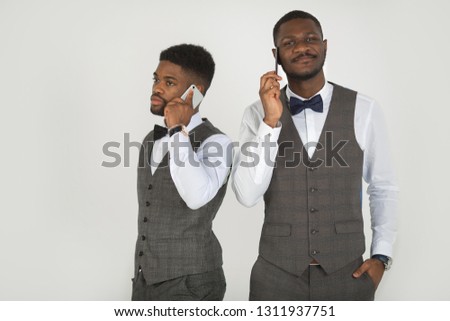two stylish african men in suits on white background talking on the phone