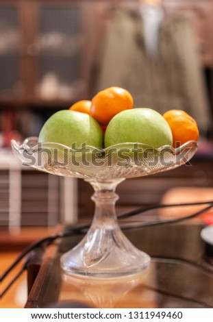 Apples and tangerine on table arranged in glass tray or bowl