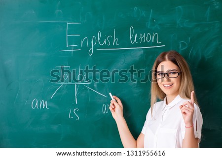 Young female english language teacher standing in front of the b Royalty-Free Stock Photo #1311955616