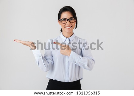 Photo of european businesswoman wearing eyeglasses standing in the office and showing copyspace isolated over white background