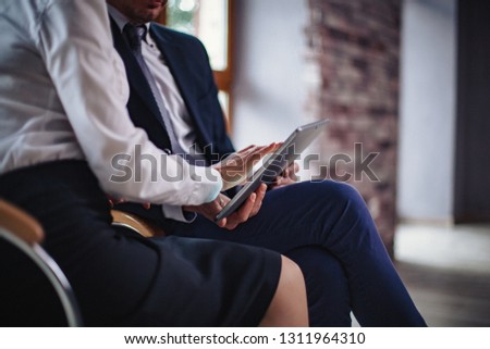 Cropped Image Of Woman In Formal Cloth Holding A Tablet While Showing Something To The College. Selective Focus On Woman's Hands Holding A Tablet At Business Meeting