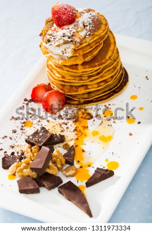 Tasty pancakes served with  fruit, honey, chocolate and whipped cream