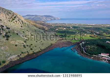 Lake Kournas with reflections and the villages of Kavallos and Mouri and Georgioupolis as well as the sea and lots of olive grove and farming aerial photography from a drone