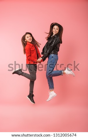 Full length photo of european girls in casual standing together isolated over red background