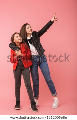 Full length photo of cheerful girls in casual standing together isolated over red background