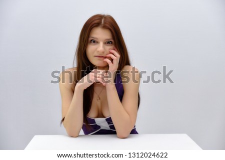 Concept studio Portrait of a beautiful young brunette girl sitting at the table on a white background and talking in different poses. She stands directly in front of the camera in various poses.