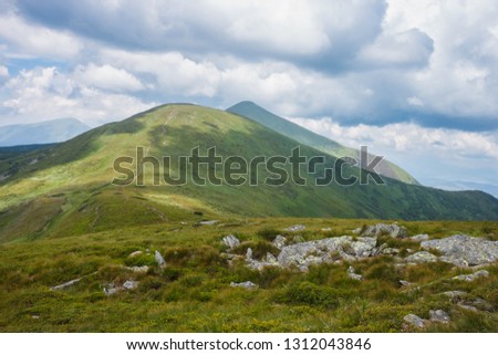 Mountain landscape. View of the mountain with green meadows against the background of beautiful clouds