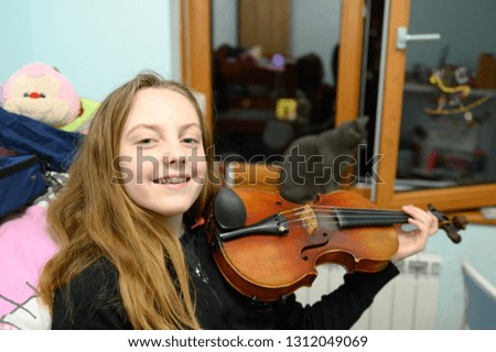 Eleven year old girl playing and practicing violin at home.