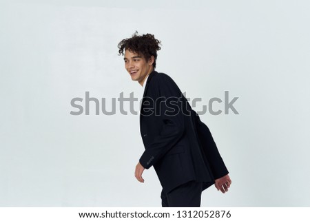 Cheerful elegant man in black suit on gray isolated background