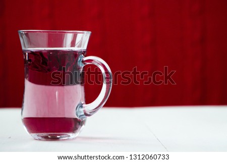 Red carcade tea in transparent glass cup at white wooden background, simple and nice drink picture for calm and peaceful rest time illustration.