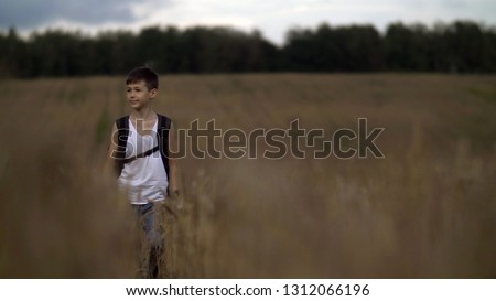 happy boy traveler with a backpack on a wheat field in the village