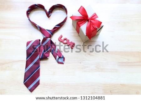 Red heart necktie and gift box with red ribbon and handmade crochet heart on wood background for happy fathers day