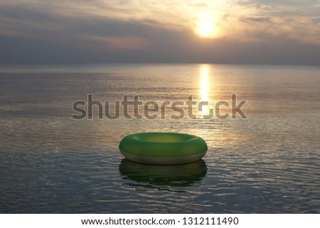 Sunset on the beach with swimming toy. Swim ring on the water in the sea at sunset.