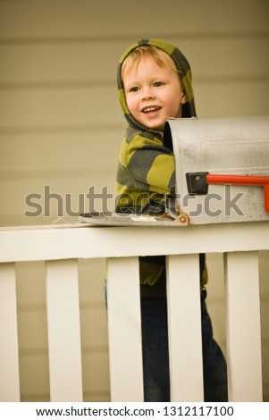 A young boy checking the letterbox.
