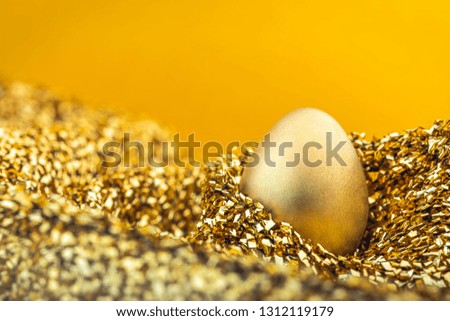Image of shiny golden egg on golden fabric