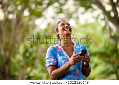 Mature woman laughing as she texts on her cellphone.