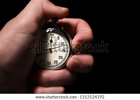 Male hand take analog stopwatch on a black background, close-up, isolate, copy space Royalty-Free Stock Photo #1312124192
