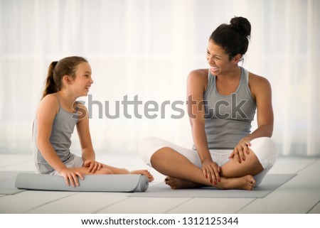 Smiling young woman sitting next to a young girl.