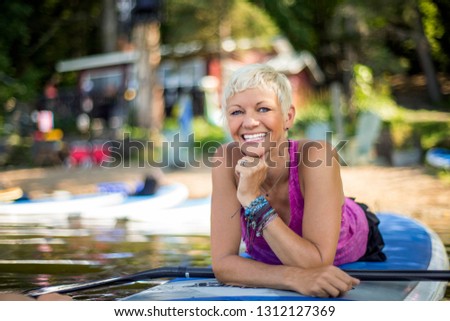 Mid adult woman prepares for paddleboarding.