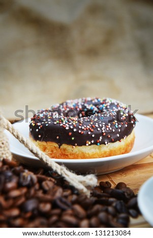 sweet donut  with chocolate icing and colored sugar on hessian  background