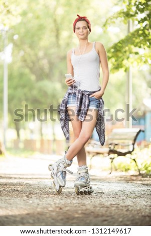 Young beautiful woman with inline skates in park posing for a camera 