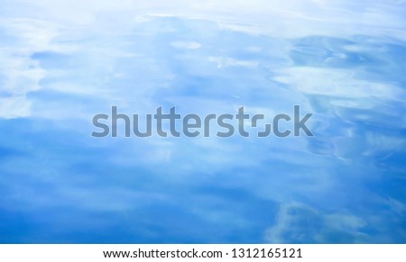 Reflection of blue sky and light white clouds shadow on shiny wavy ripple river water surface.  Abstract blue and white natural freeform wave pattern background, dreamy screen, natural theme template.
