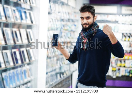 Yes, i found it! Indian beard man customer buyer at mobile phone store choose his new smartphone. South asian peoples and technologies concept. Cellphone shop.